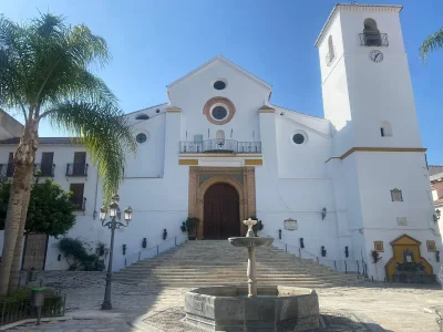 Iglesia de San Juan Bautista de Coín de día, con su torre y la fuente de la plaza