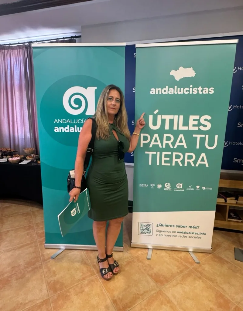 Cristina RJ Osorio junto a los carteles «Útiles para tu tierra» de Andalucía Por Sí - Andalucistas
